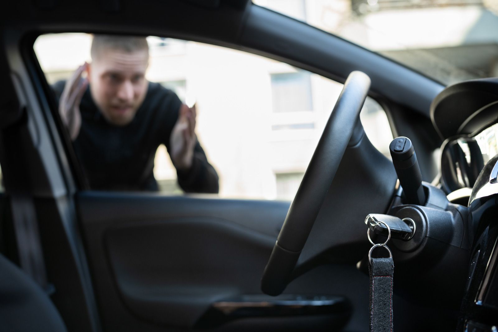 A man is looking through the window of a car.