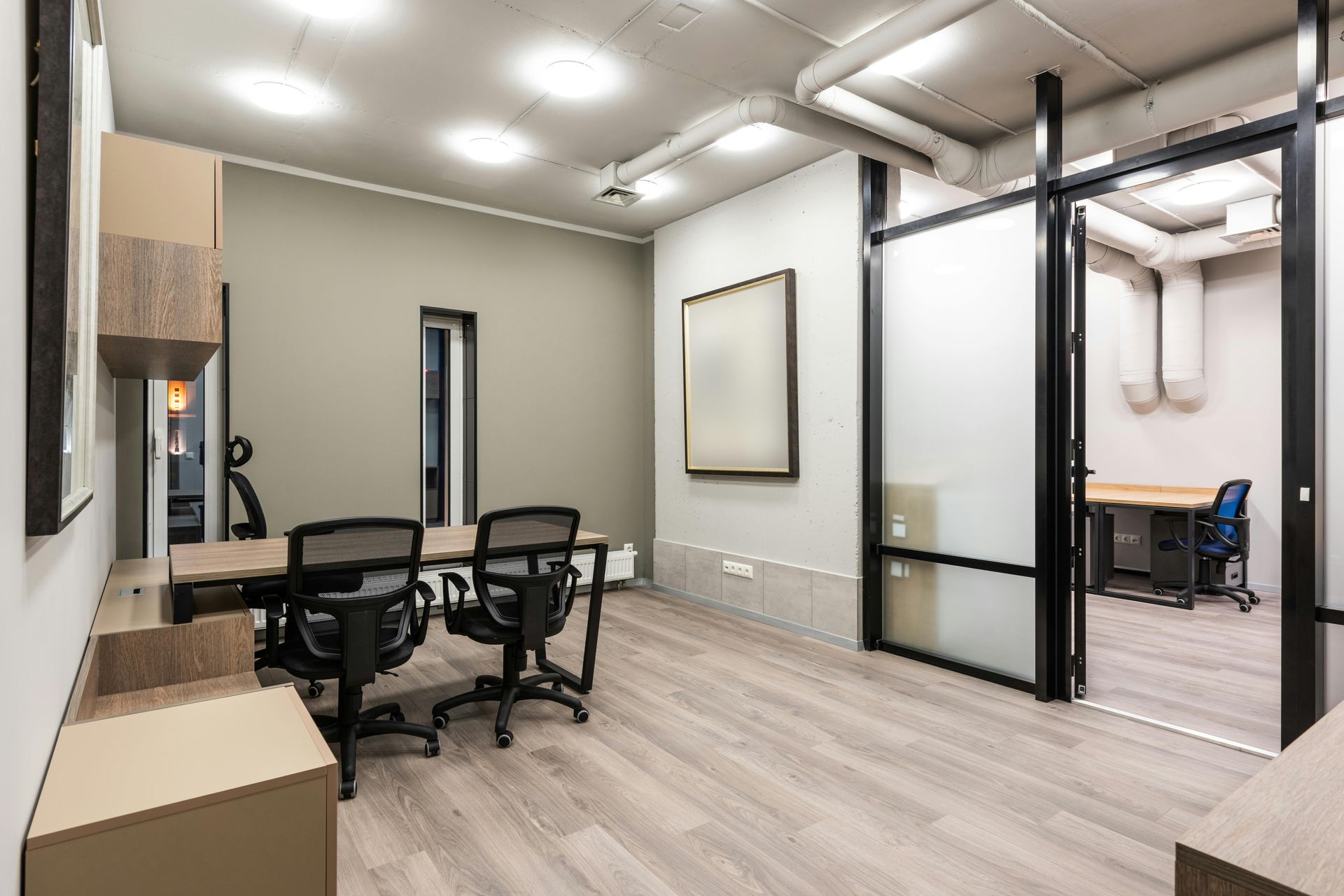 An office interior with a conference table, chairs, and frosted glass door to a second room.