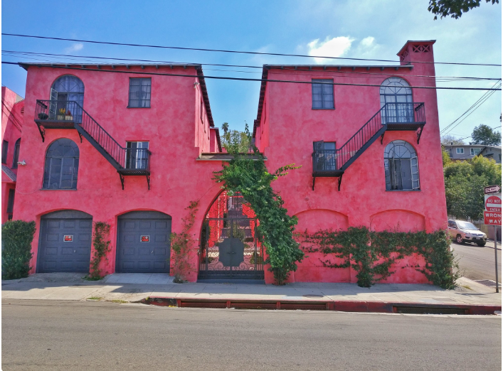 Bright pink stucco buildings with arched windows and black metal staircases.