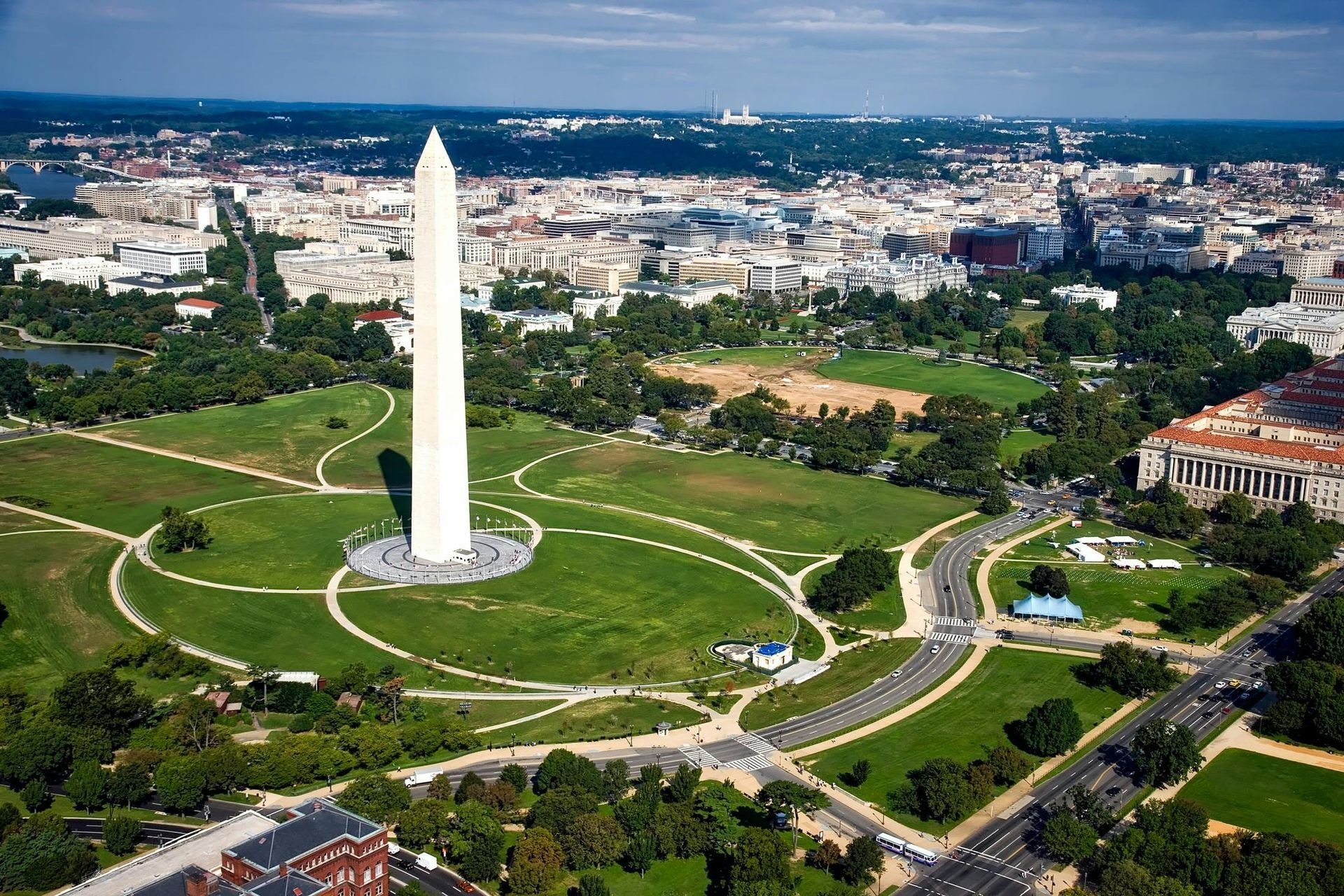 Washington Monument stands on the National Mall in Washington, D.C., with surrounding green space and city buildings.