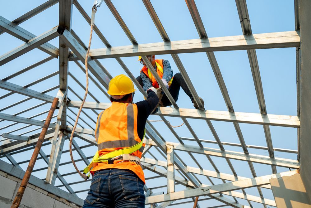 Two construction workers are working on a metal structure.