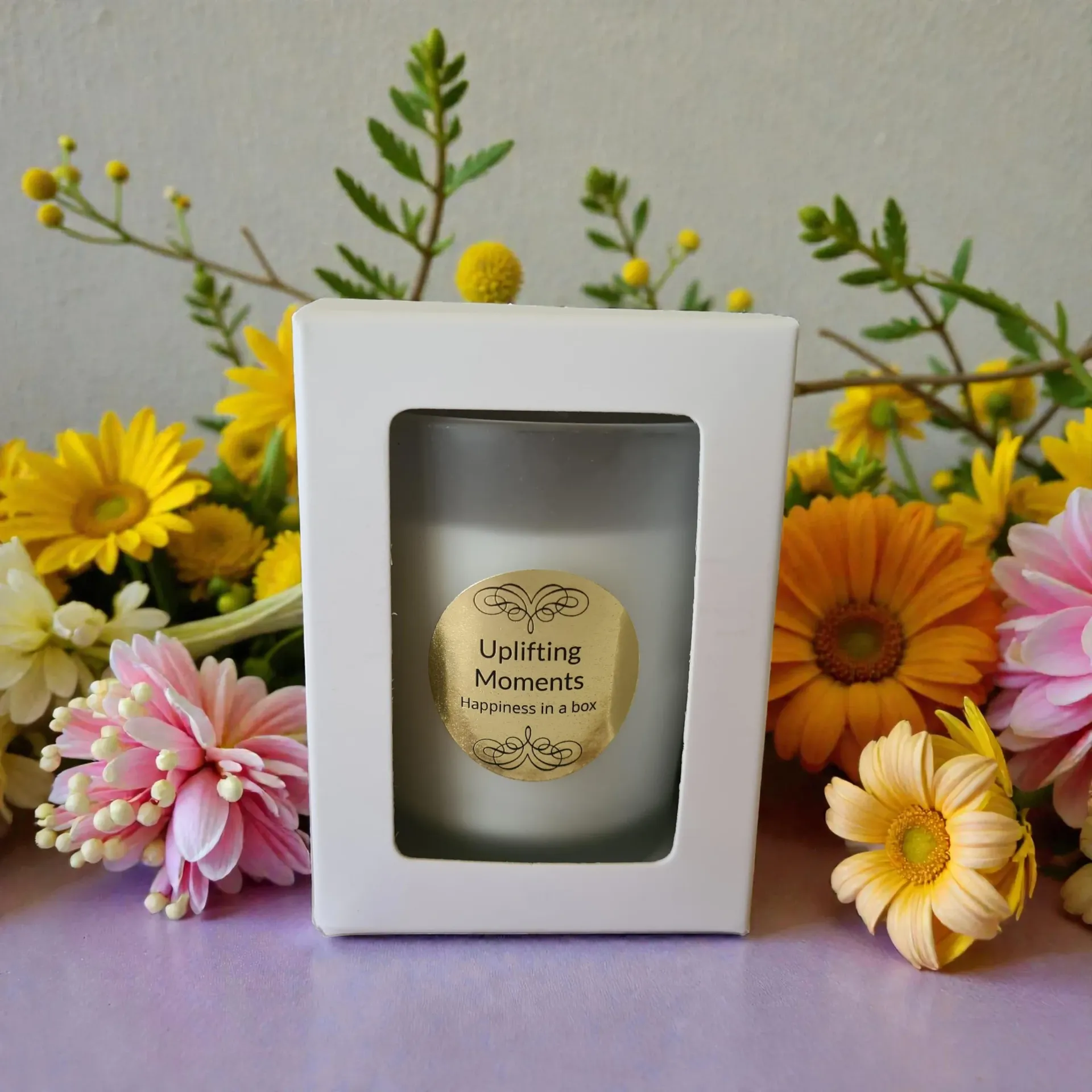 A white candle with a gold label reading 