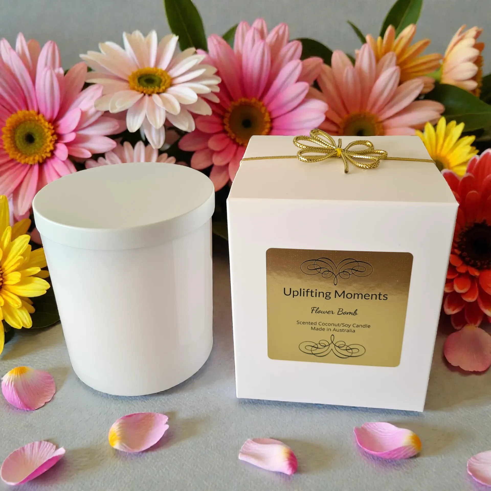 White candle with lid, surrounded by pink flowers on a wooden surface.