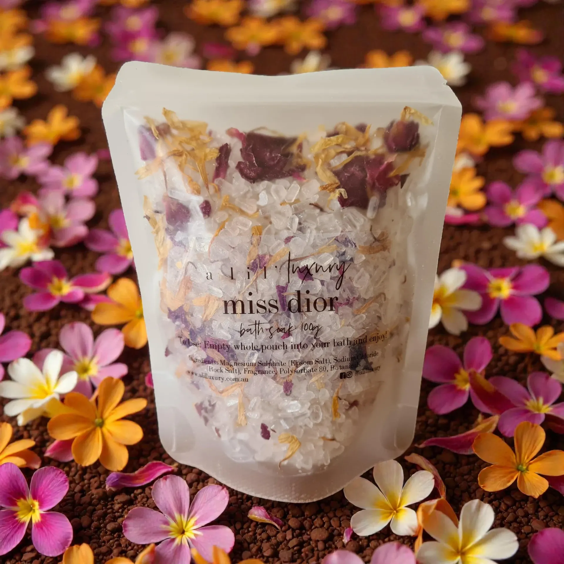 Bag of bath salts with dried flowers, on a bed of colorful flowers.