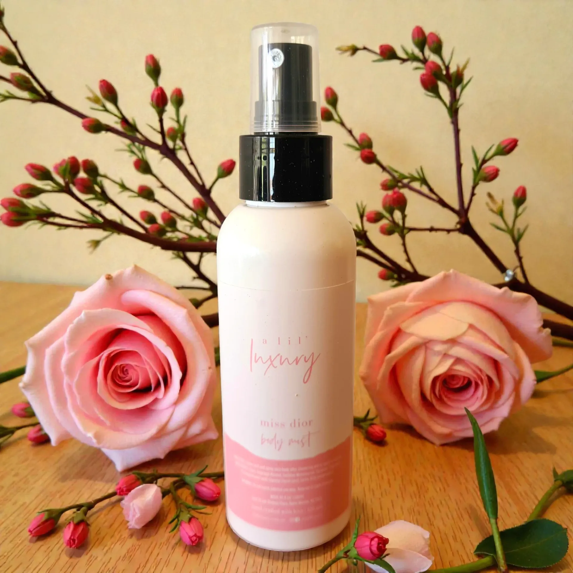 Body mist bottle with pink roses and branches on a wooden surface.