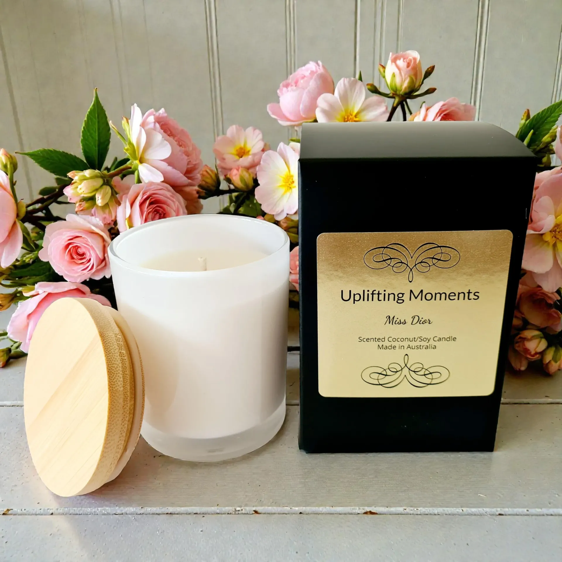 White candle, macaron, and roses on a white wooden surface. Soft lighting, floral arrangement.