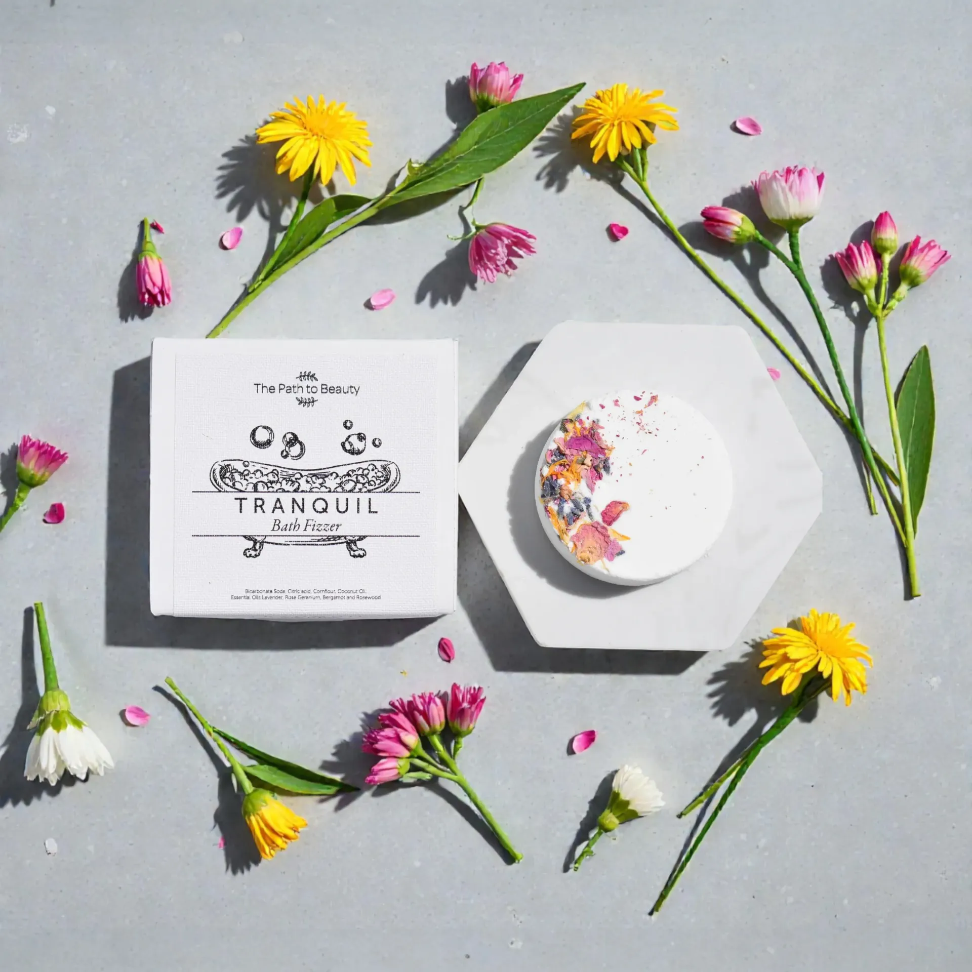 Soap and floral arrangement. White soap box and round soap with flowers on a gray surface, surrounded by flowers.