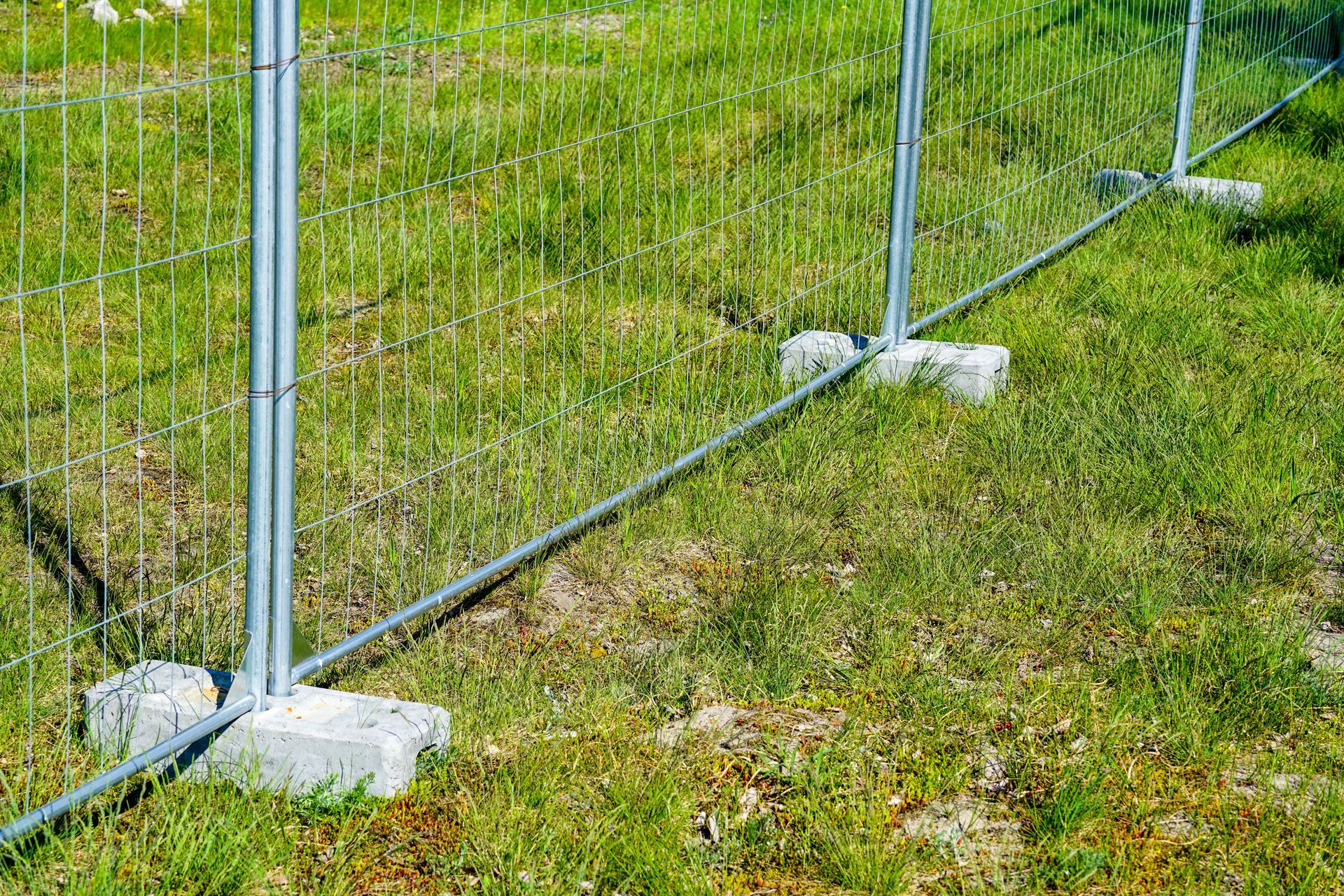 Temporary metal fence on grassy ground, securing an area.