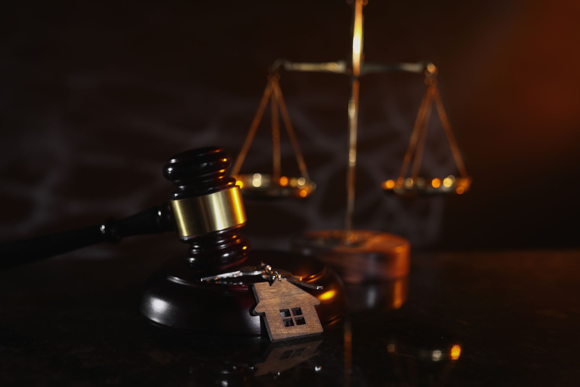 Gavel and scales of justice, with small house model, symbolizing legal proceedings related to property.