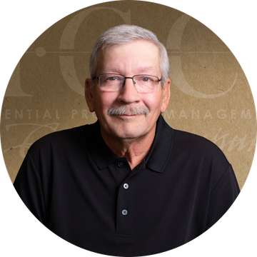 Man with glasses and mustache, wearing a black collared shirt, smiling.