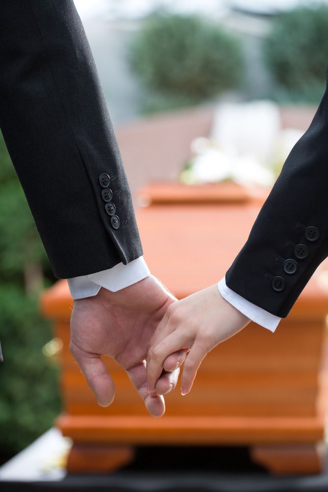 Couples At Funeral Holding Hands Consoling Each Other In View Of The Coffin — Create A Personalised Funeral On The Central Coast, NSW