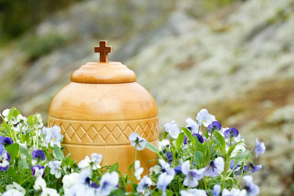 Cremation Urn Surrounded By Blue Violets Ready For Spreading The Ashes In Nature — Trusted Funeral Directors On The Central Coast, NSW