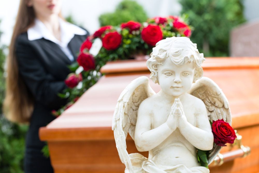 Mourning Woman On Funeral With Red Roses Standing At Casket Or Coffin — Create A Personalised Funeral in Sydney, NSW