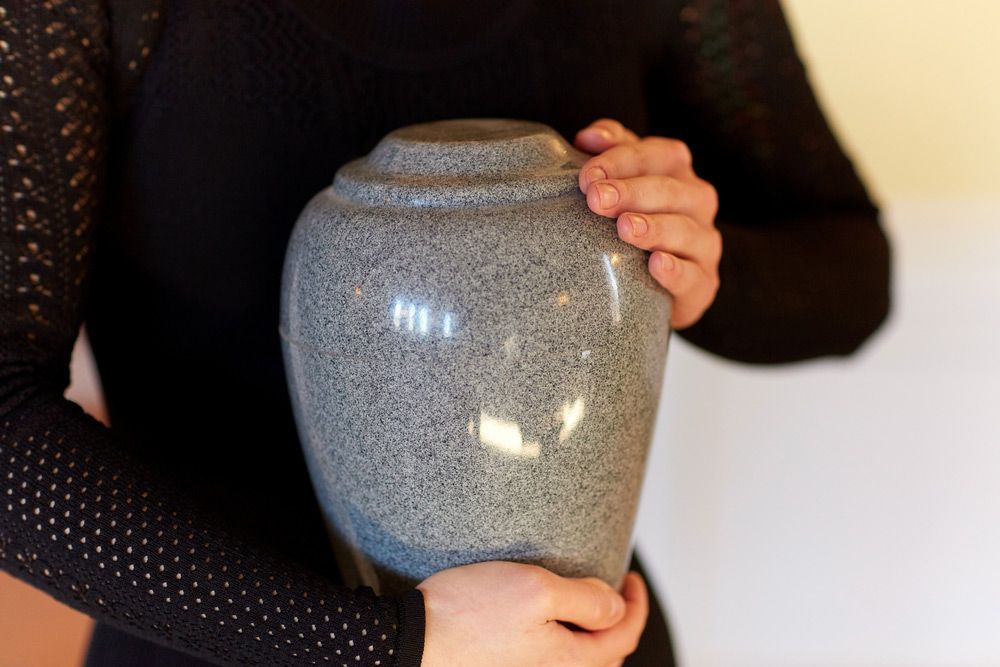 Woman With Cinerary Urn At Funeral — Explore Our Packages For Cremation On The Central Coast, NSW