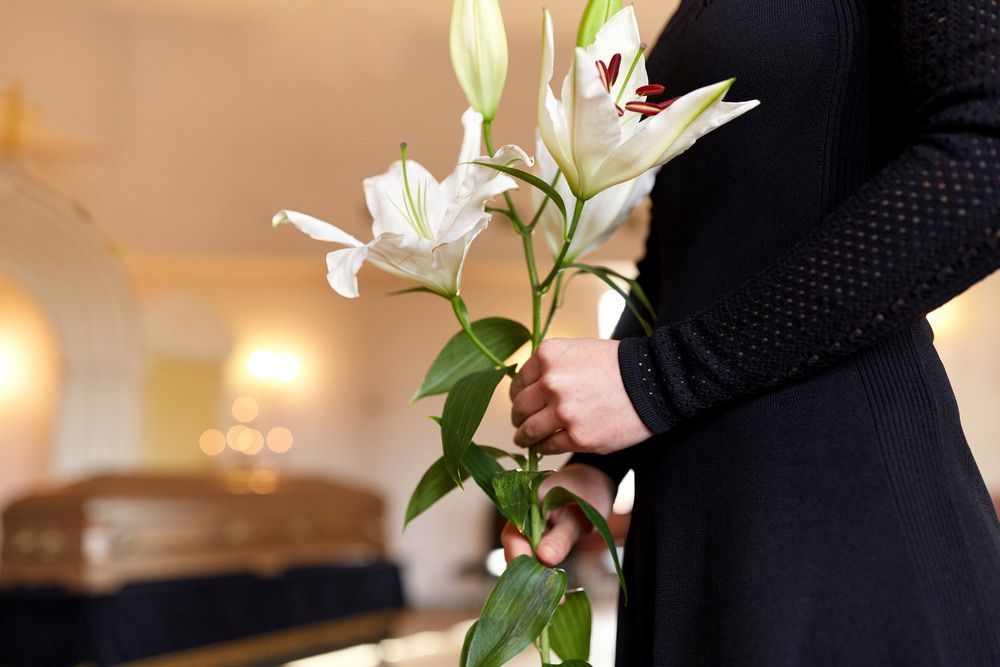 Woman With White Lily Flowers And Coffin At Funeral — Create A Personalised Funeral On The Central Coast, NSW