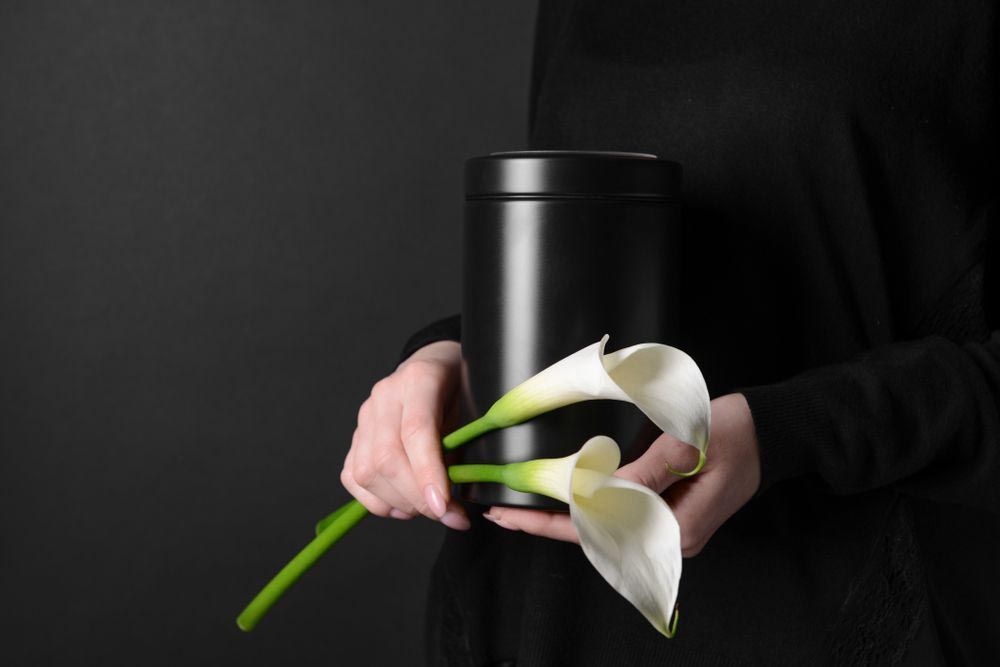 Woman Holding A Black Urn And Flowers