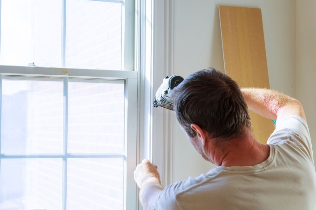 a man is installing tiles on a wall in a bathroom .