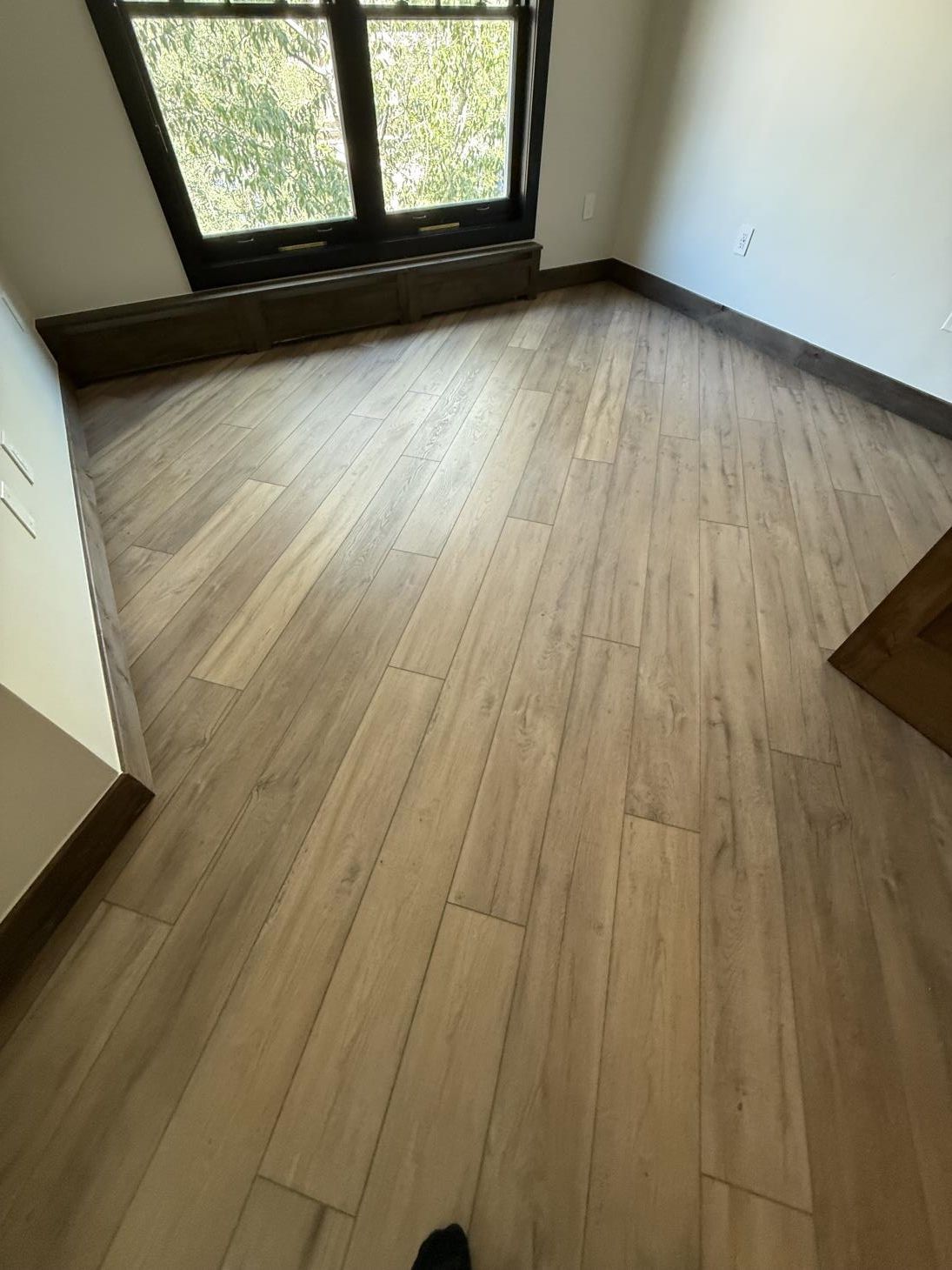 A cozy family room featuring a two-story fireplace as the focal point, set against the backdrop of warm hardwood floors.