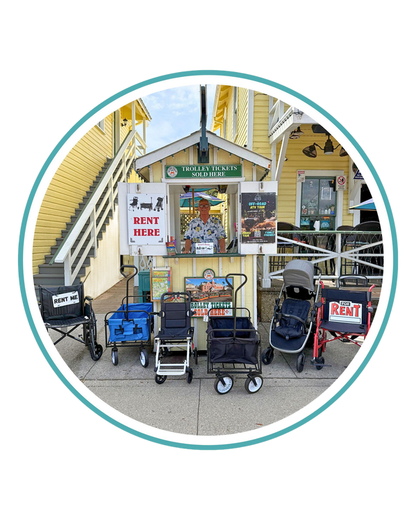 A small rental kiosk in front of a yellow building offering wheelchairs, strollers, and wagons for rent.