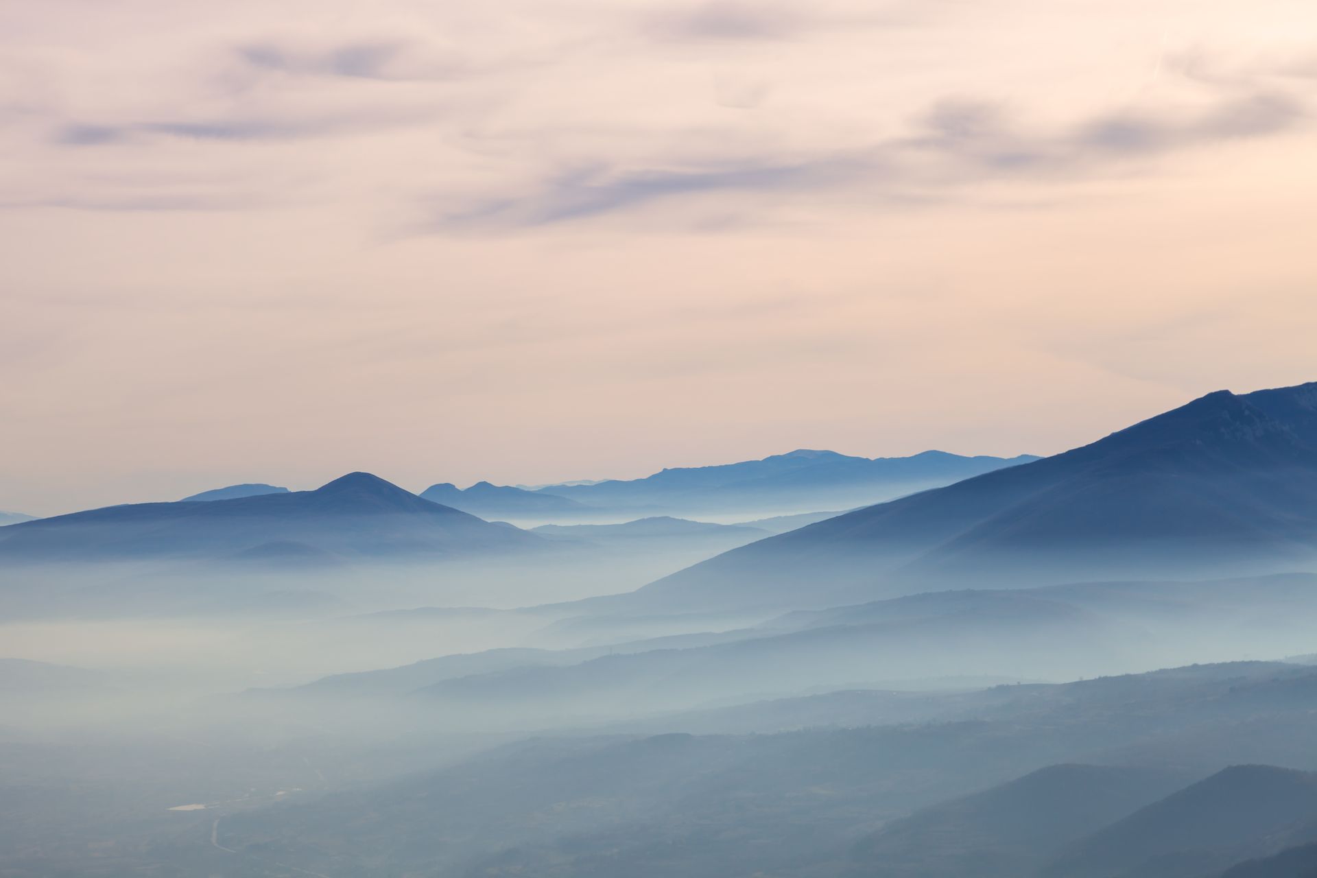 A sunset over a mountain range with a lot of fog