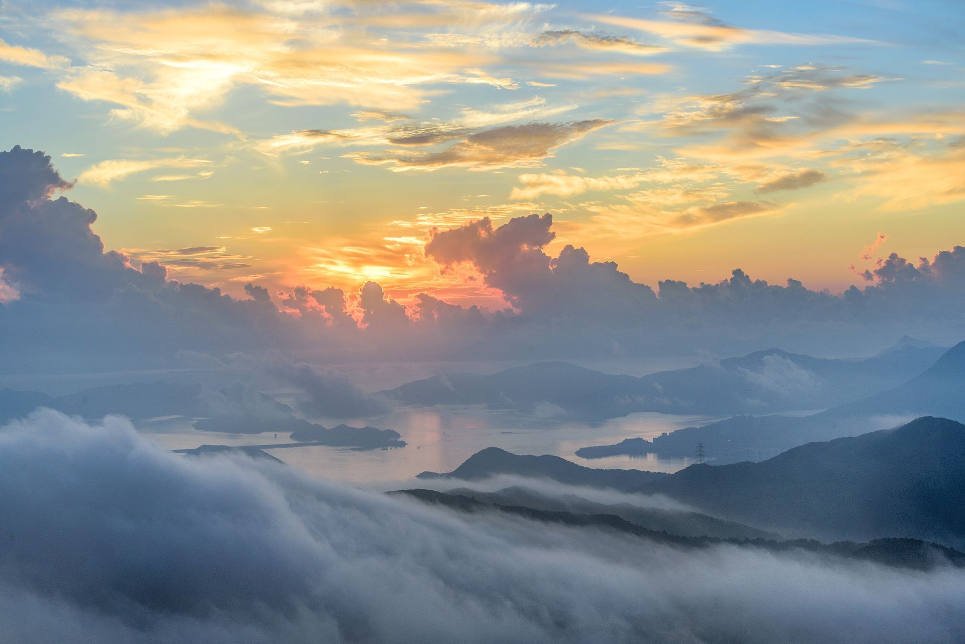 A sunset over a mountain range with a lot of fog