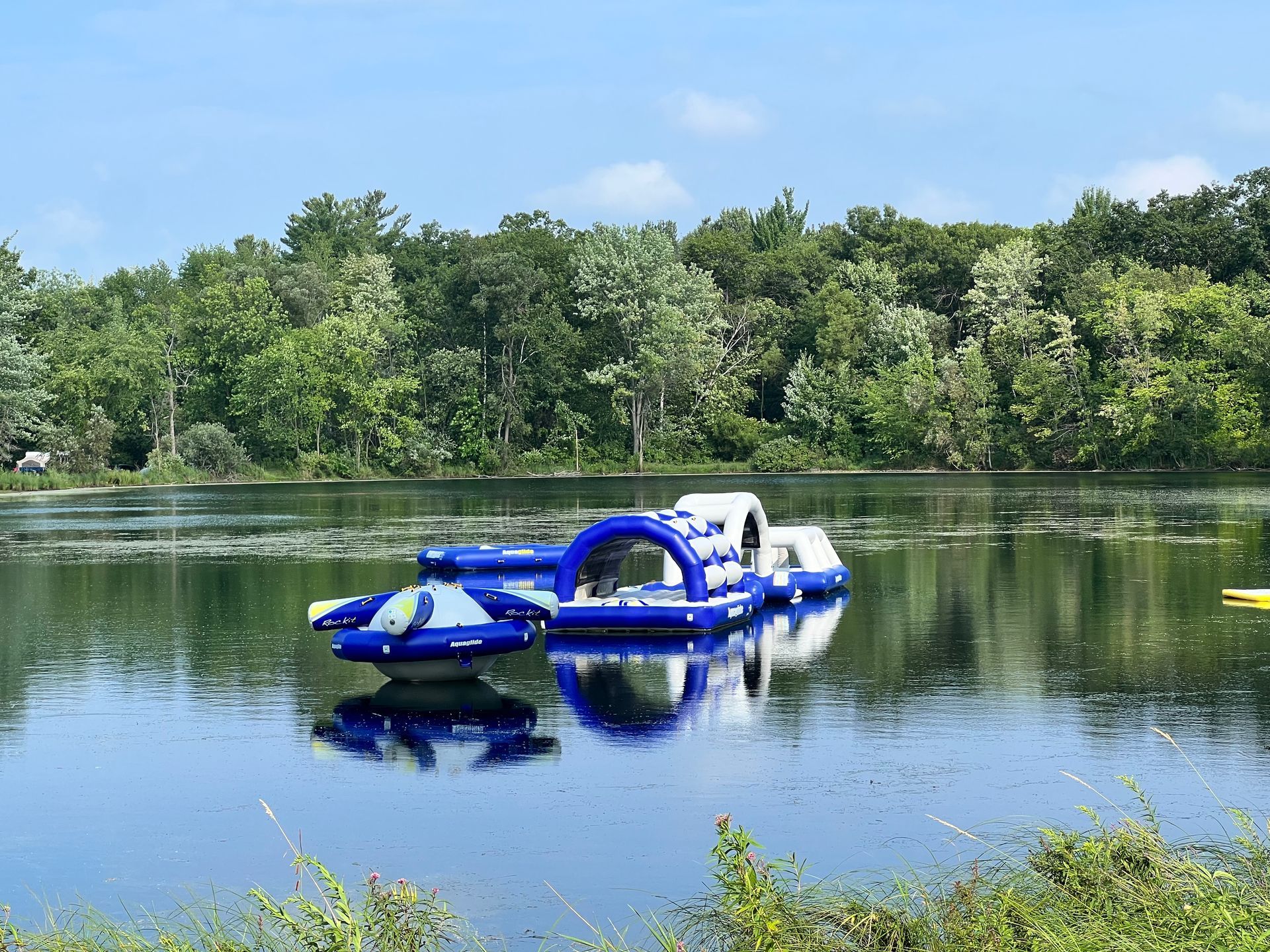 A large inflatable raft is floating on top of a lake surrounded by trees.