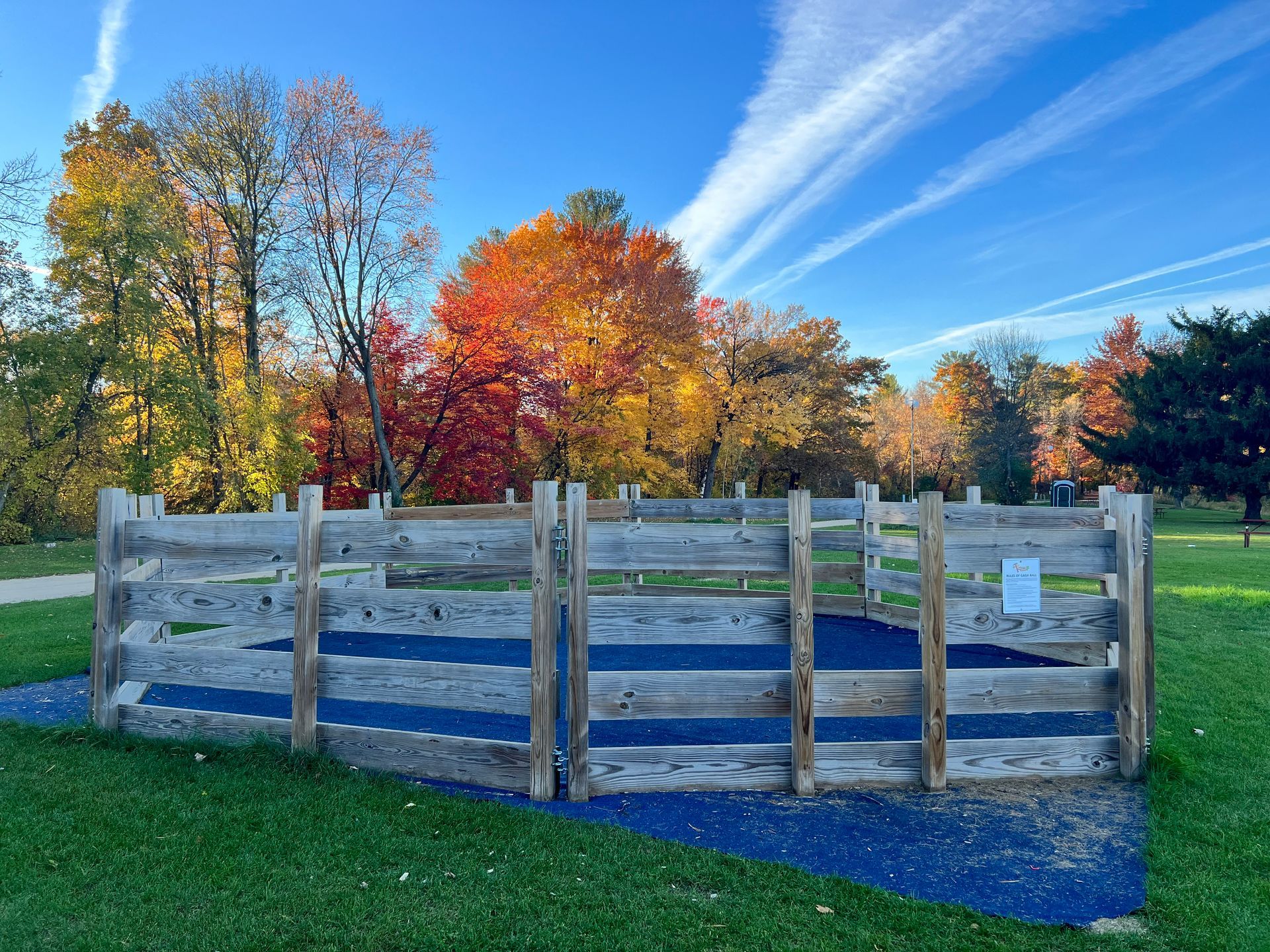A wooden fence in a park with trees in the background