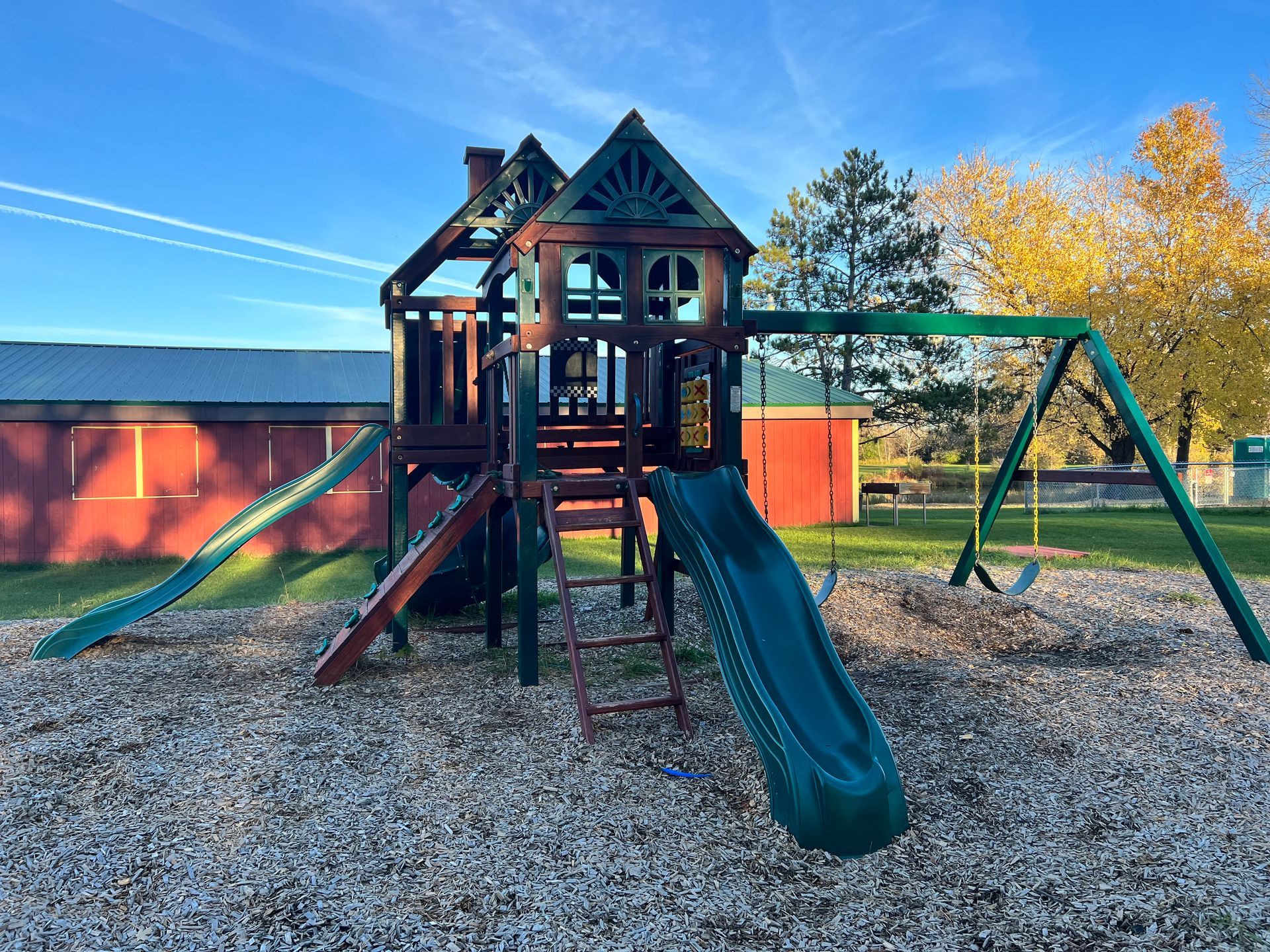 A playground with a slide and swings in a park.