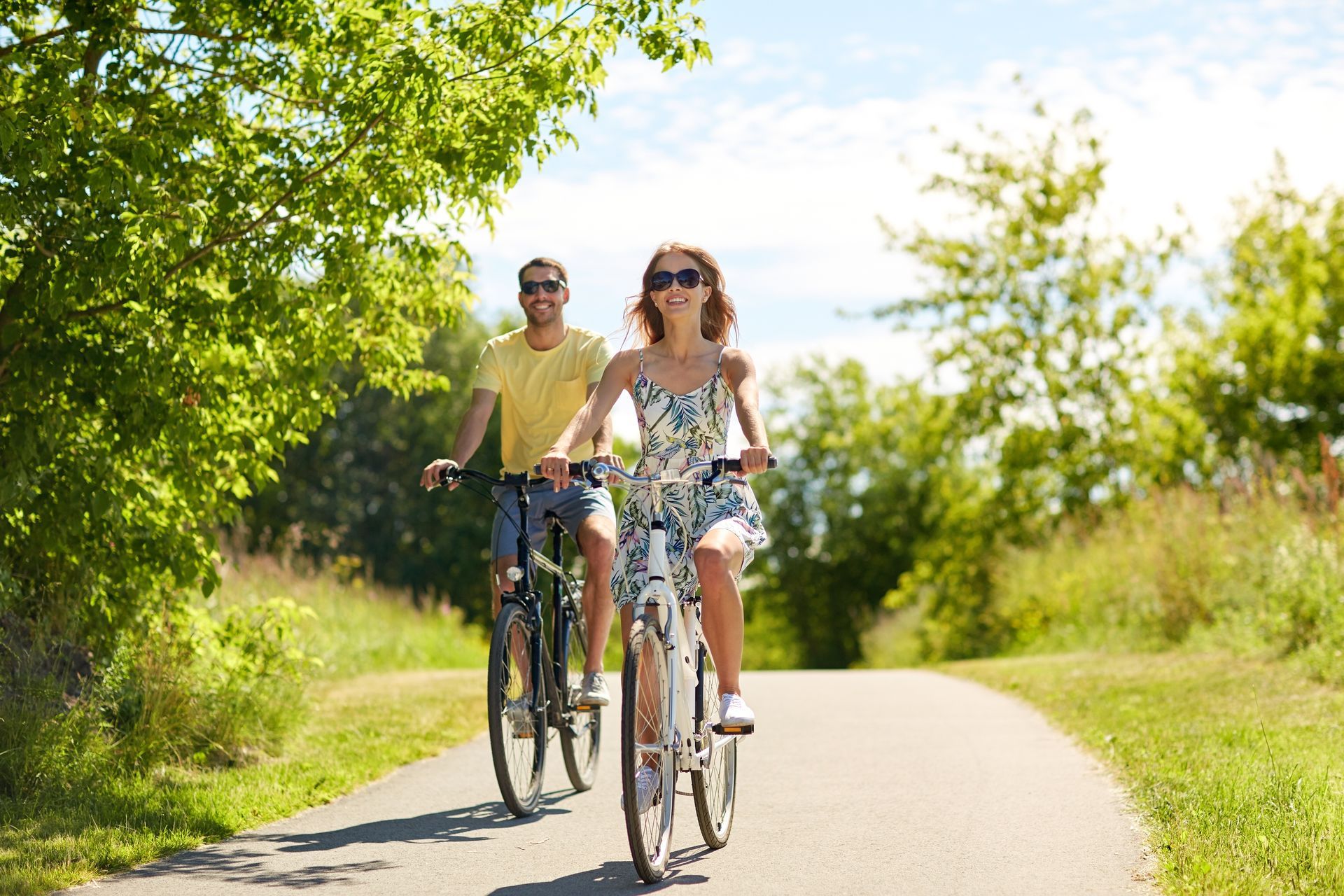 A man and a woman are riding bicycles down a path.
