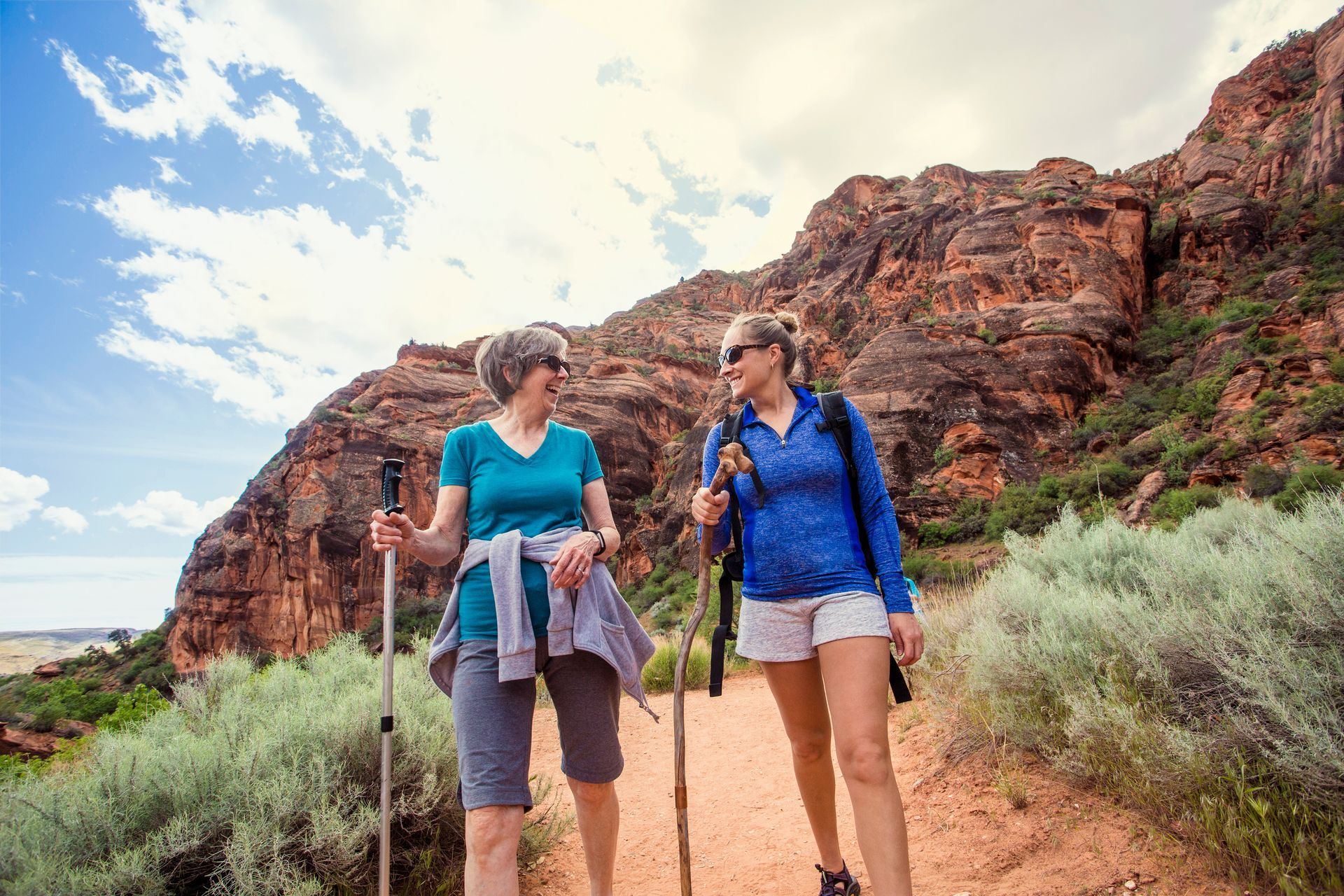 Two women are hiking in the mountains and talking to each other.