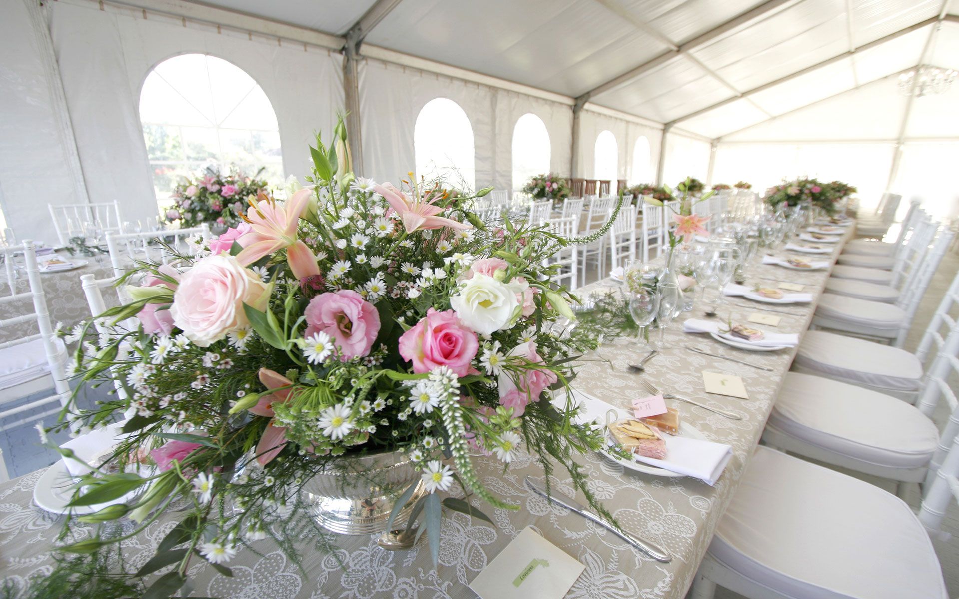 A long table with a vase of flowers on it in a tent.