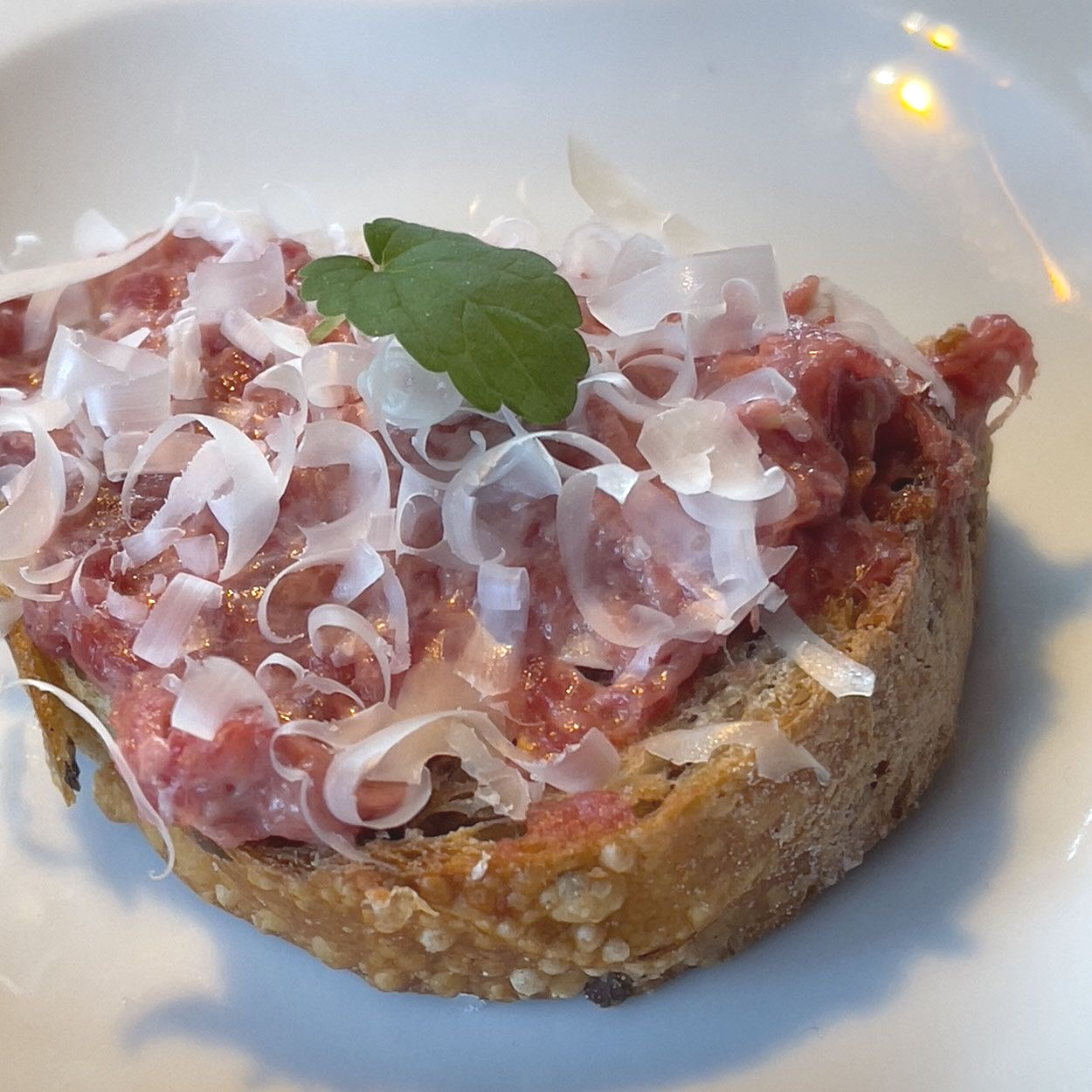 Eine Nahaufnahme von einem Sandwich mit Fleisch und Käse auf einem weißen Teller