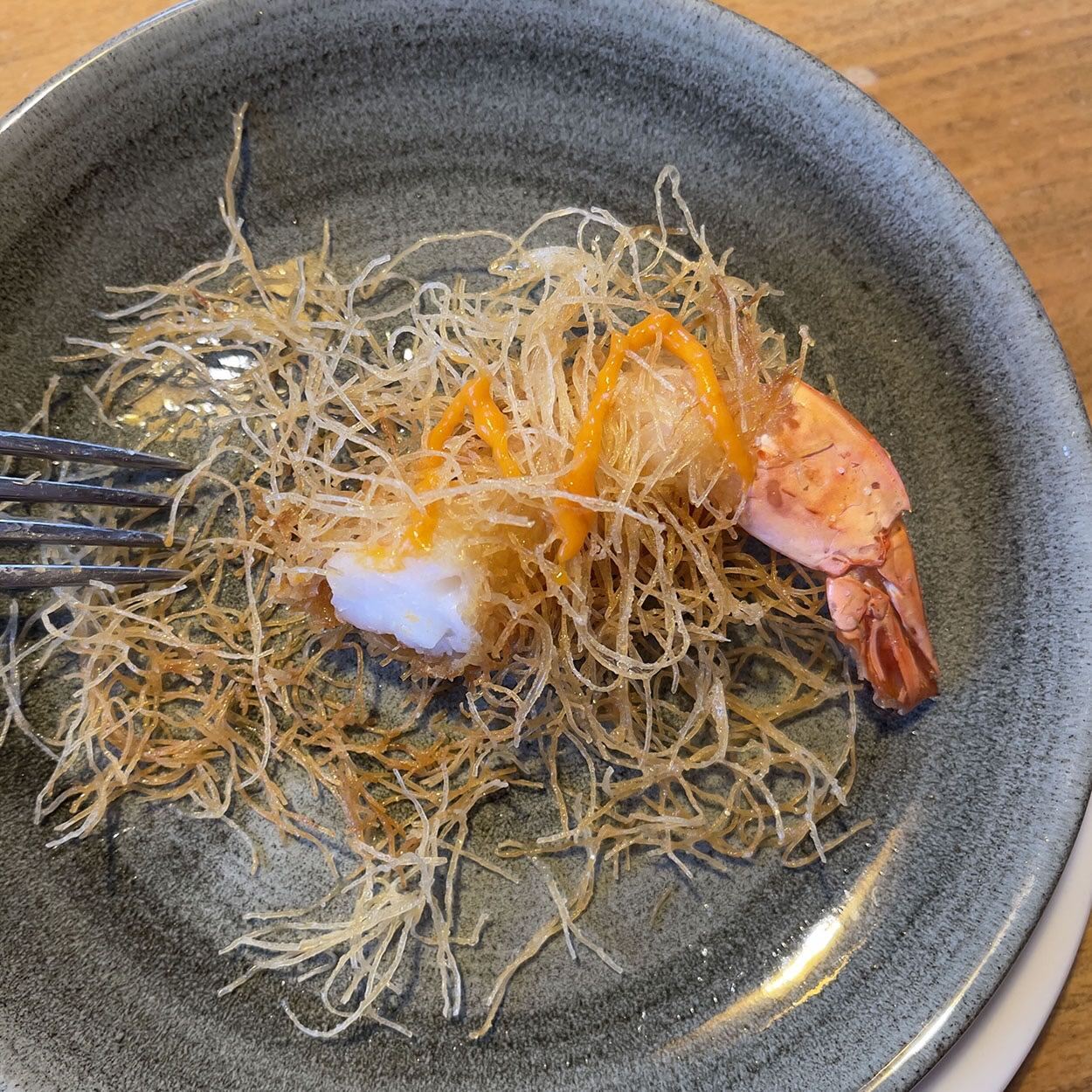 Ein Teller mit Garnelen und Nudeln und einer Gabel