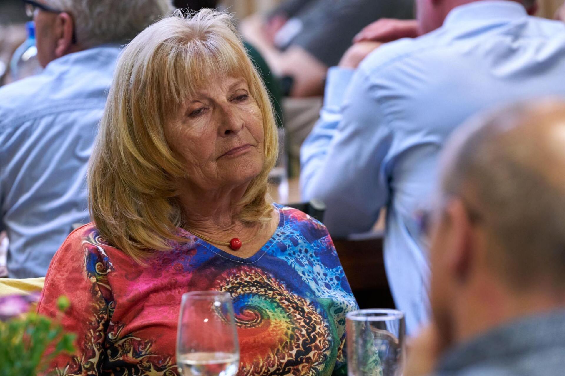 Eine Frau sitzt mit einem Glas Wein an einem Tisch.