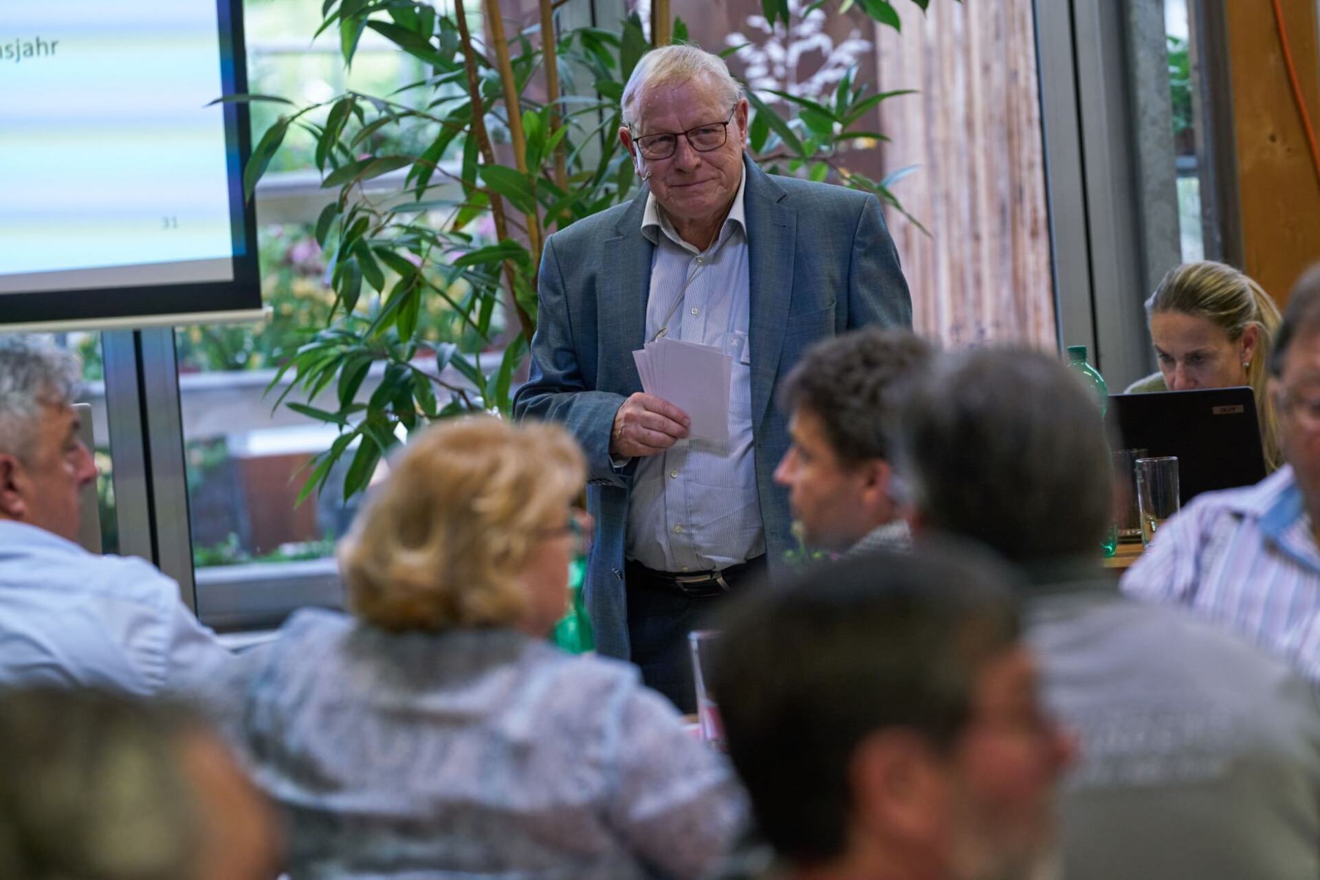 Ein Mann hält vor einer Gruppe von Leuten in einem Raum eine Präsentation.