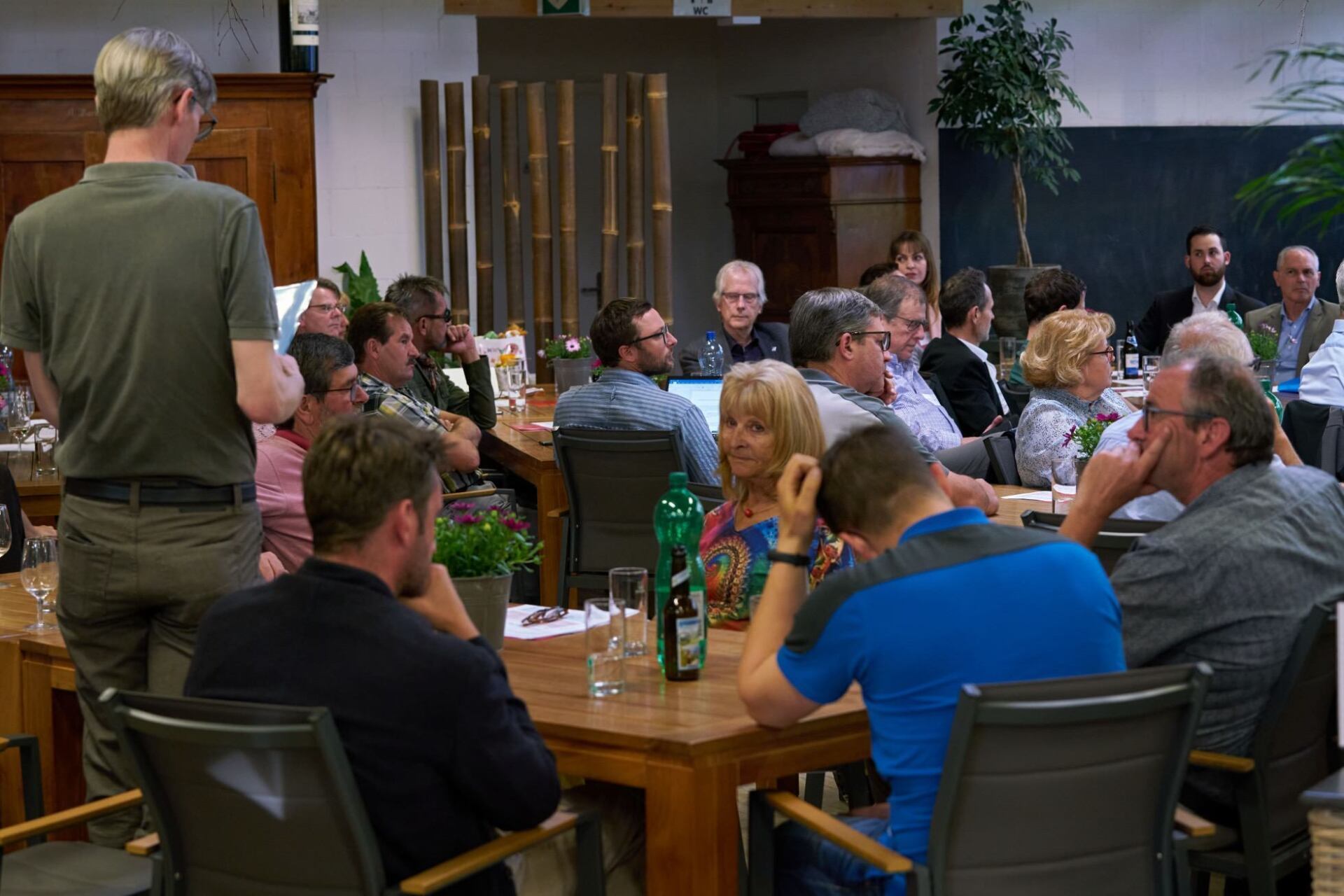 Eine Gruppe von Leuten sitzt in einem Raum an Tischen.