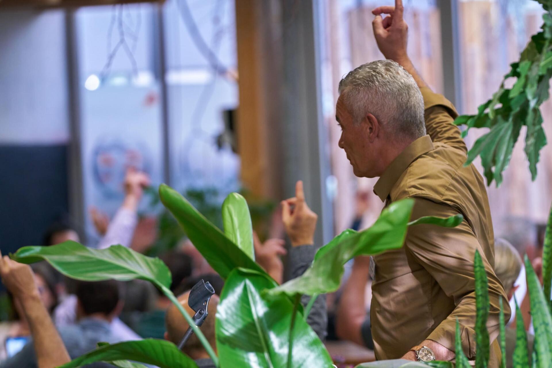 Ein Mann steht mit erhobenen Armen vor einer Menschenmenge.