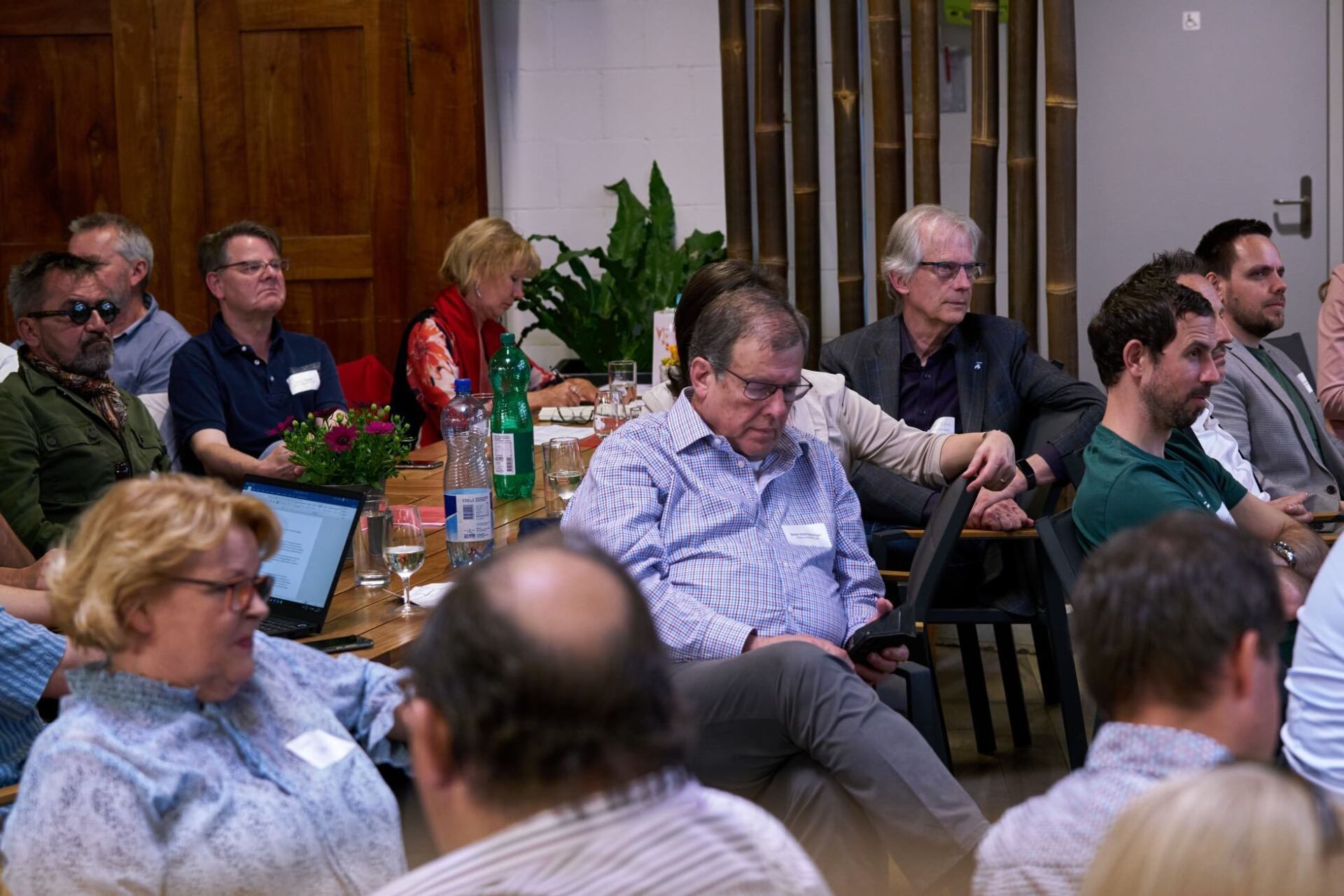 Eine Gruppe von Leuten sitzt in einem Raum an einem Tisch.
