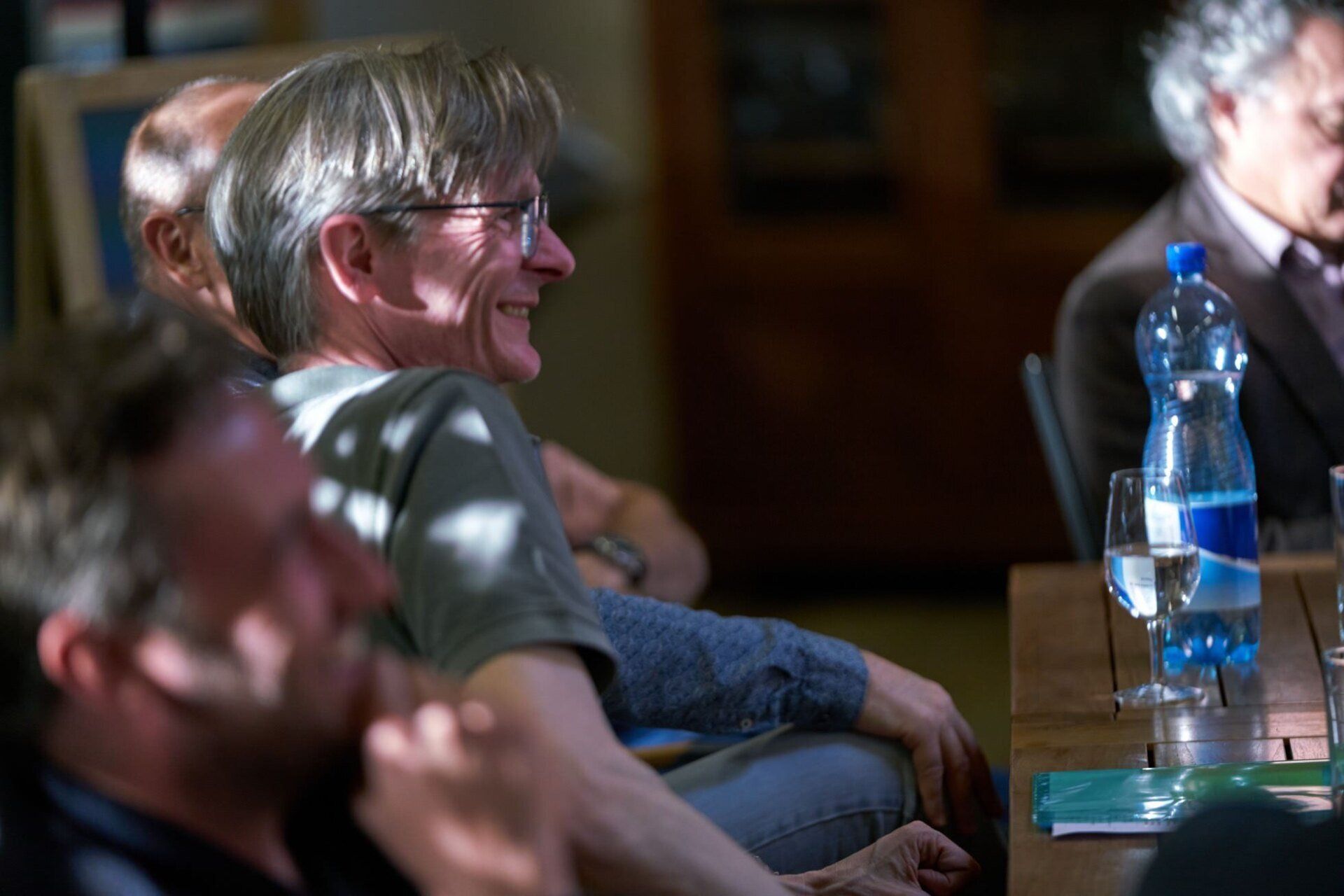 Eine Gruppe Männer sitzt mit Wasserflaschen an einem Tisch.