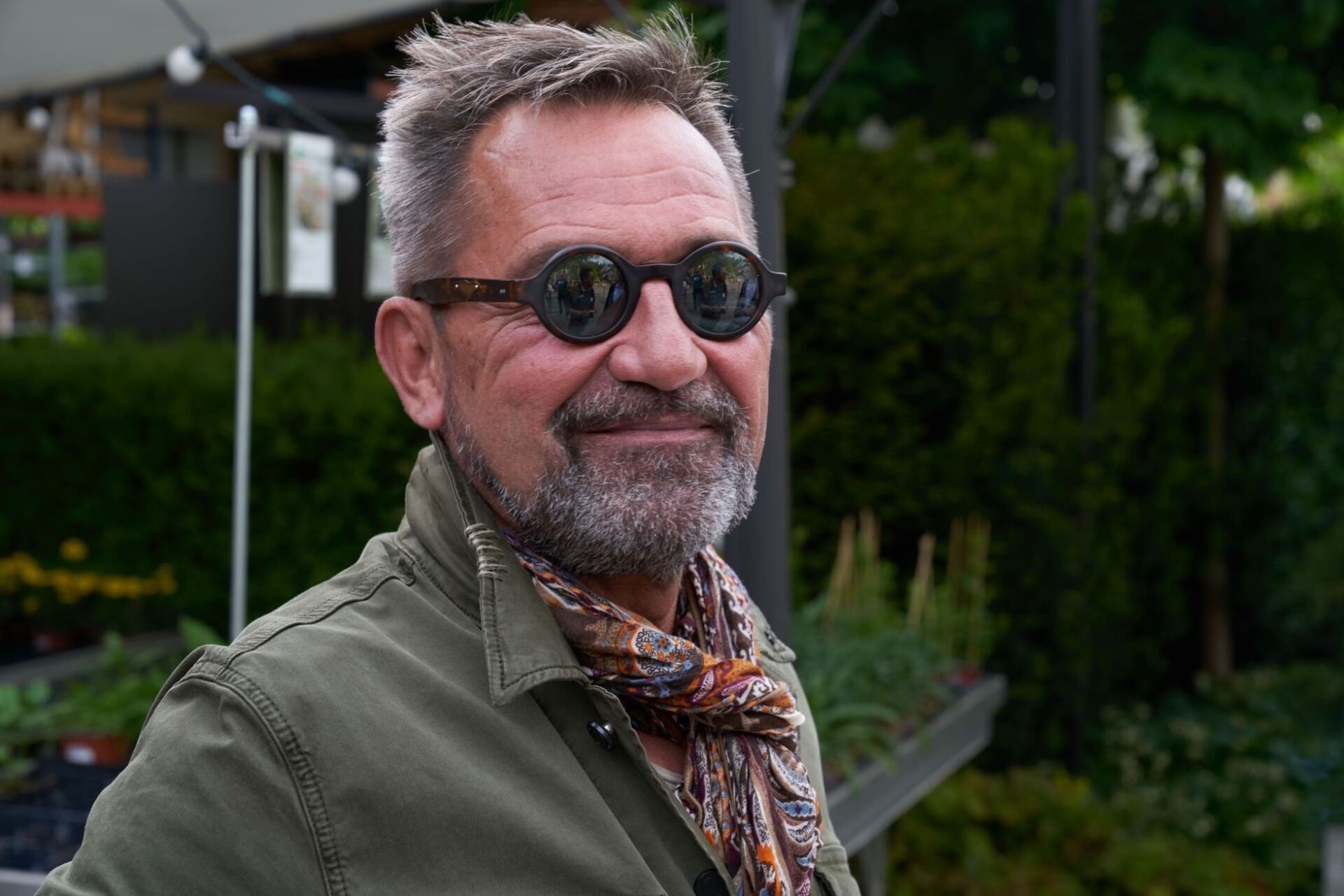 Ein Mann mit Bart, Sonnenbrille und Schal.