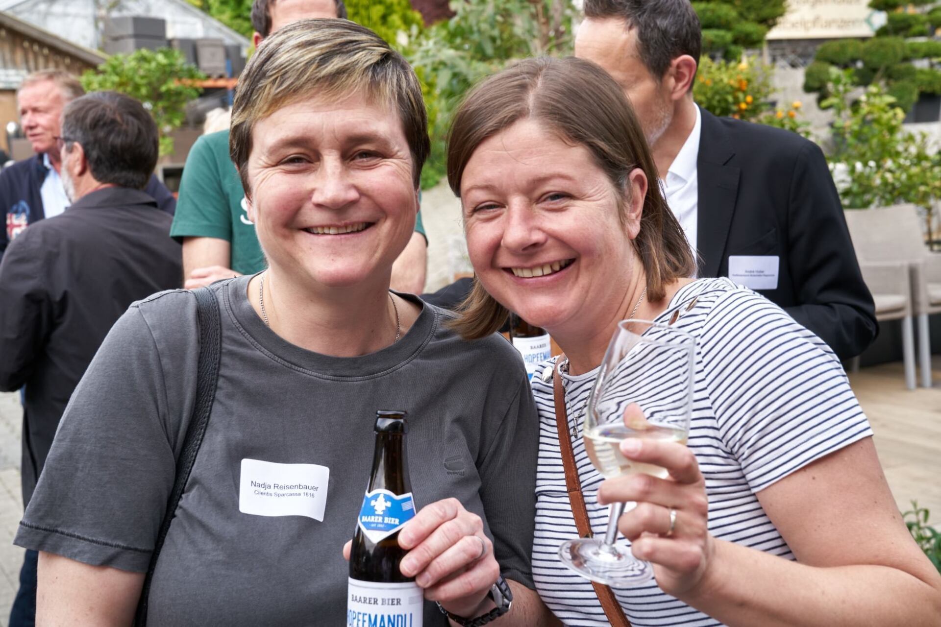 Zwei Frauen halten eine Flasche Bier und ein Glas Wein.