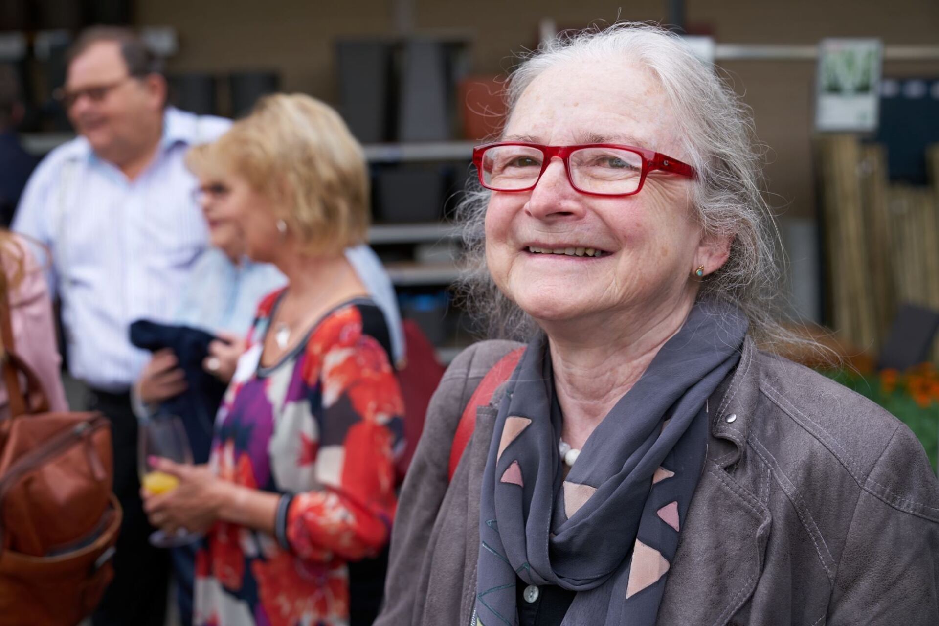 Eine Frau mit Brille und Kopftuch lächelt in einer Menschenmenge.