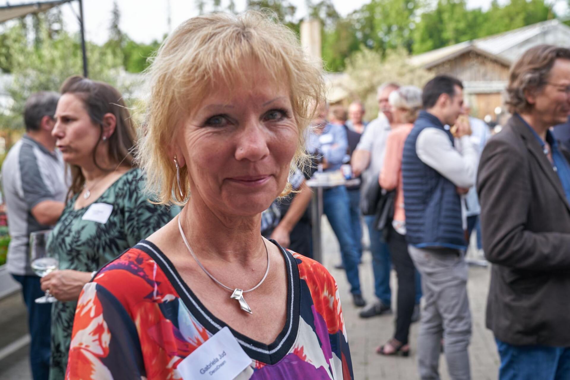 Eine Frau mit einem Namensschild steht in einer Menschenmenge.