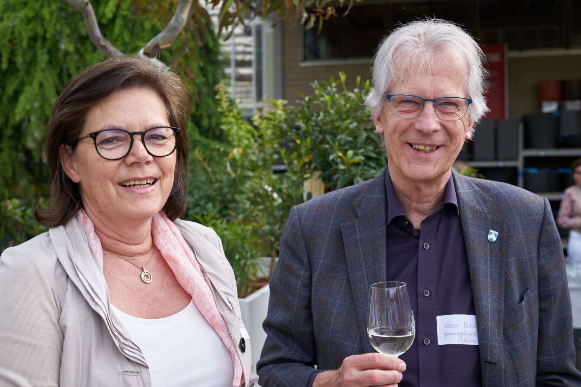 Ein Mann und eine Frau stehen nebeneinander und halten Weingläser in der Hand.