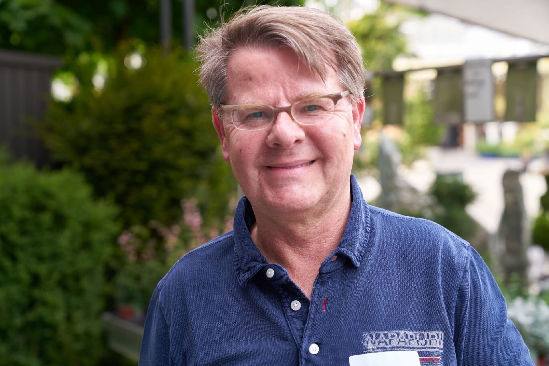 Ein Mann mit Brille und blauem Hemd lächelt in die Kamera.