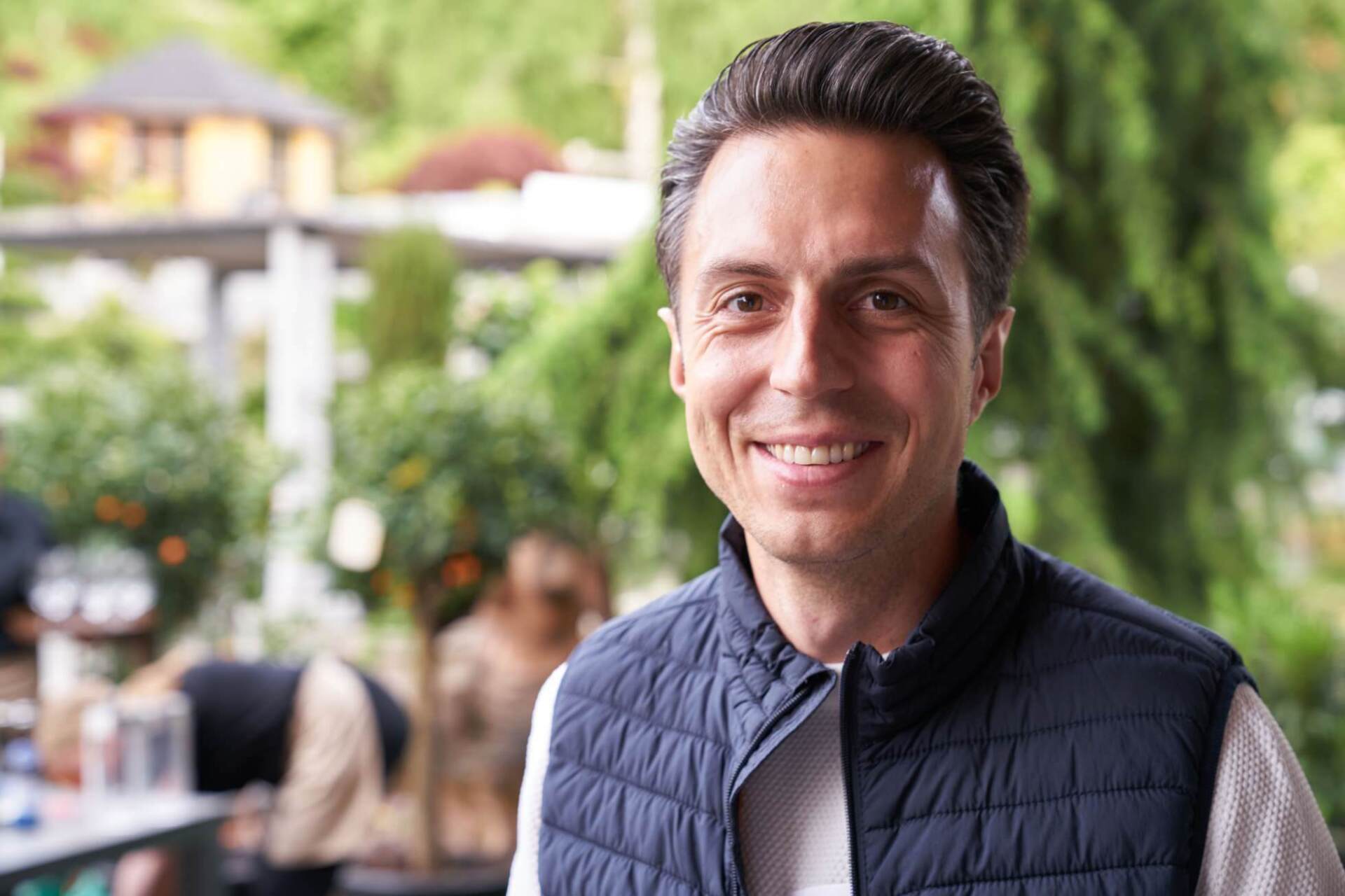 Ein Mann in einer blauen Weste lächelt in die Kamera.