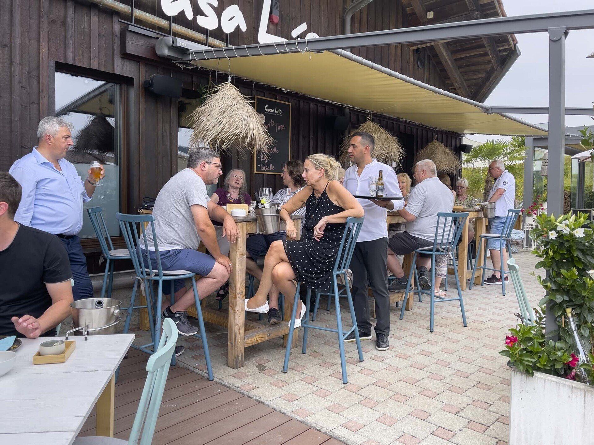 Eine Gruppe von Leuten sitzt an Tischen vor einem Restaurant.