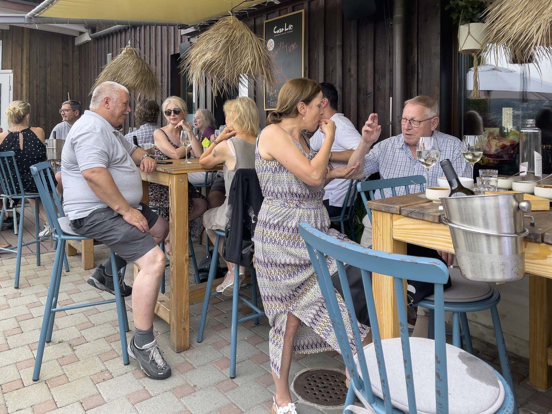 Eine Gruppe von Leuten sitzt an Tischen vor einem Restaurant.