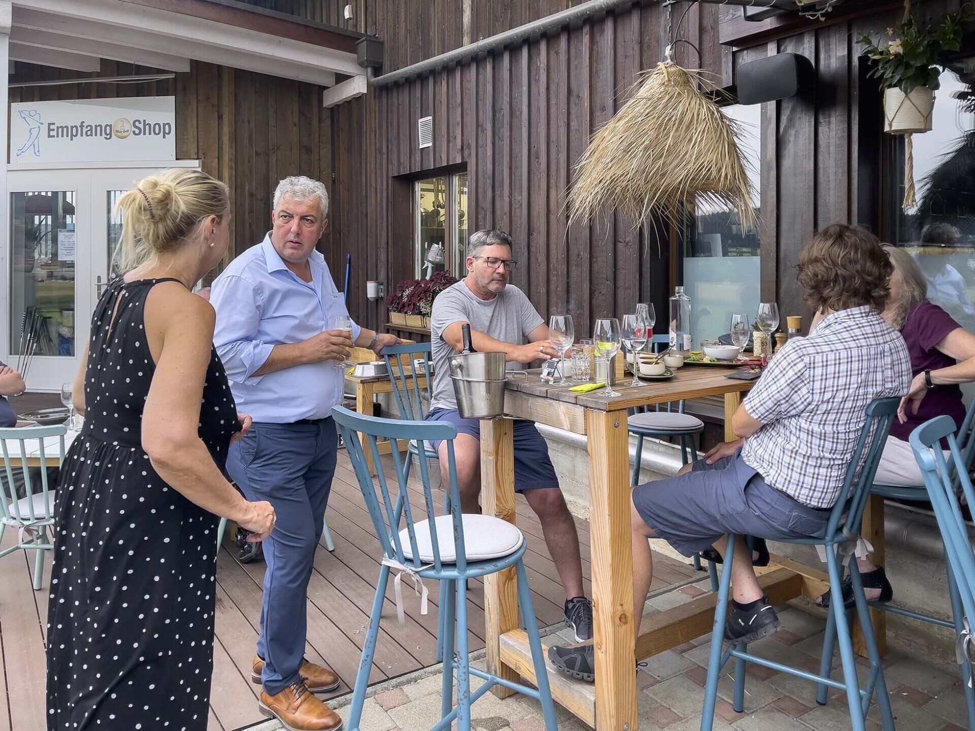 Eine Gruppe von Leuten sitzt an Tischen vor einem Restaurant.