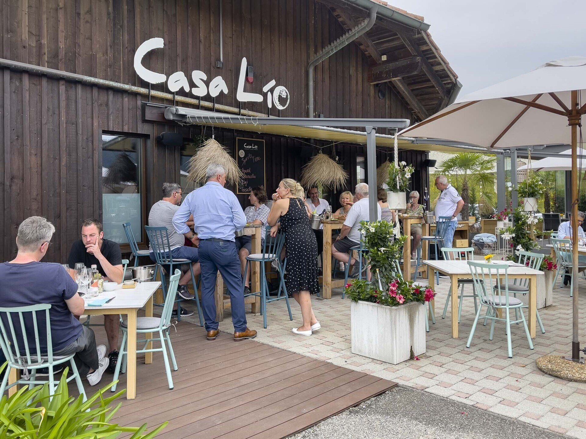 Eine Gruppe von Leuten sitzt an Tischen vor einem Restaurant.